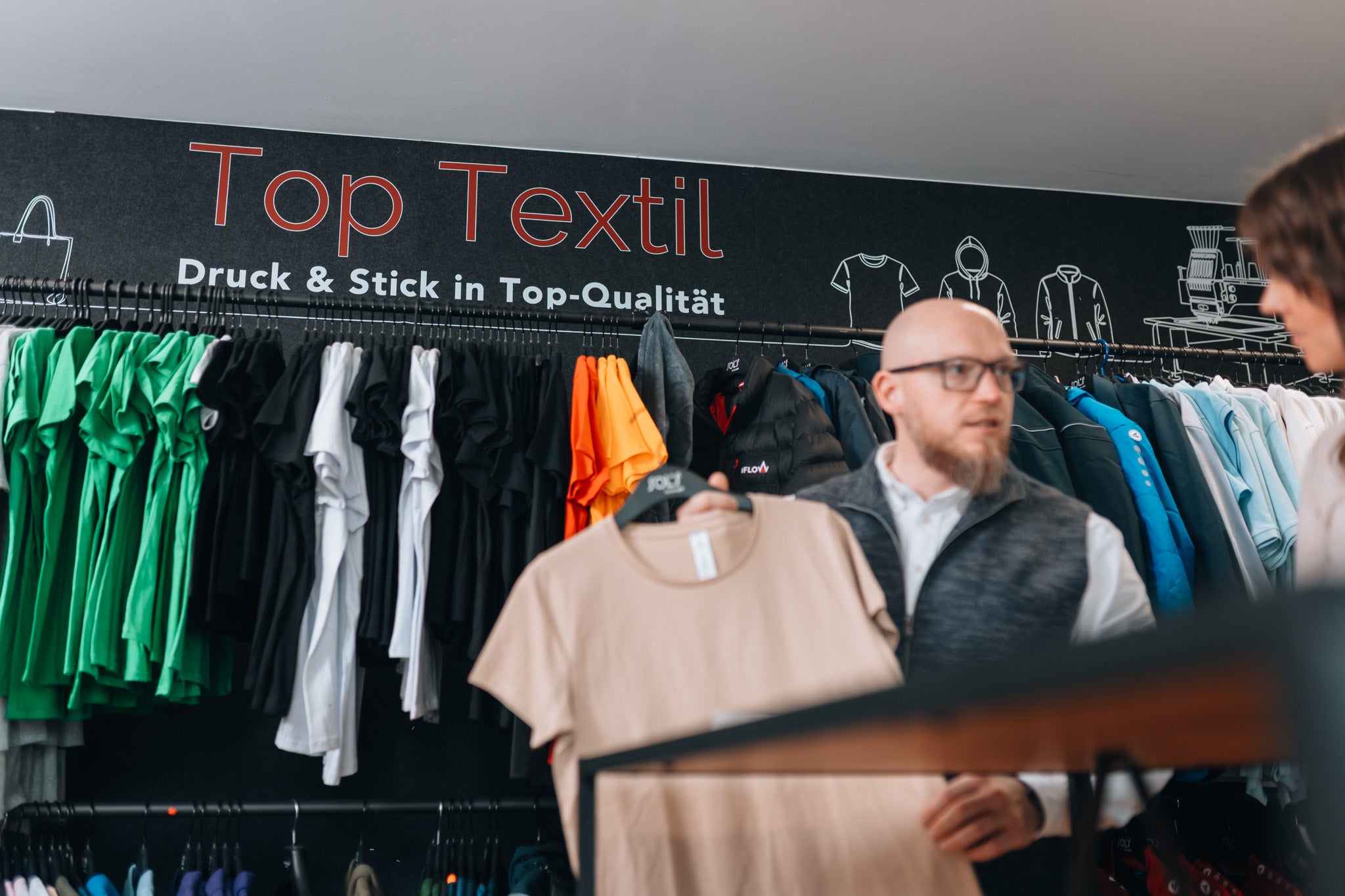 Präsentation eines T-Shirts vor der Top Textil Markenwand für Textilveredelung